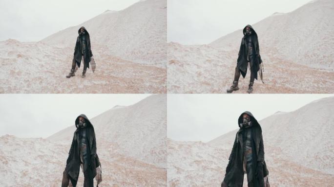 广角后启示录女性在黑色兜帽斗篷和垃圾防护防毒面具站在死谷沙漠的山丘上。蒸汽朋克，赛博朋克，核战争后的
