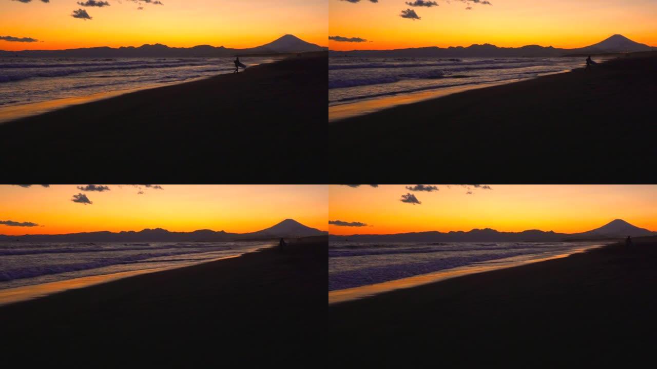 日落时的海滩和冲浪者。富士山和日落时的沙滩