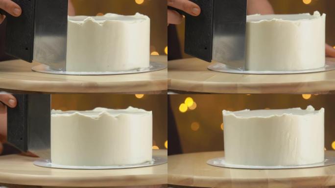 糕点厨师的特写镜头用刮刀将蛋糕上的奶油抹平