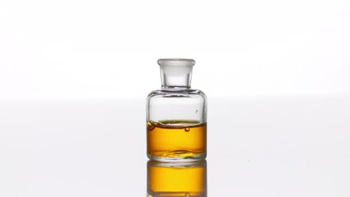 摩洛哥坚果油落入带有黄色液体的透明瓶中