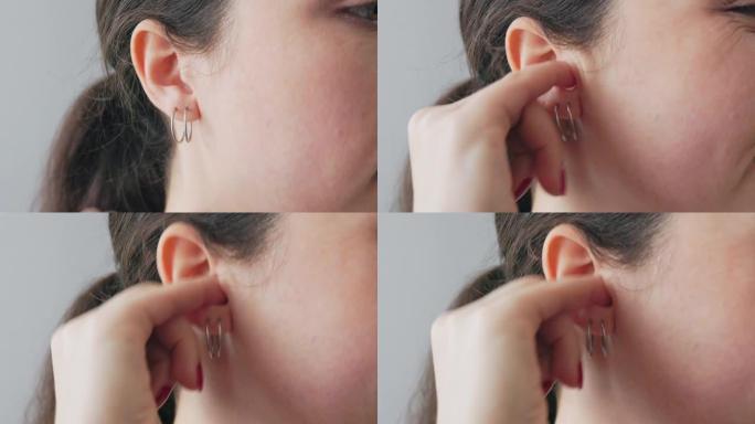 一个用手指用耳环在耳朵里抓挠的女人的脸部特写。耳痛和耳聋的概念