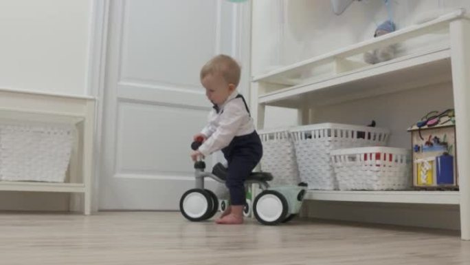 庆祝他的第一个生日的孩子收到了一个平衡自行车作为礼物，男婴在婴儿平衡自行车为1岁的孩子骑玩具。
