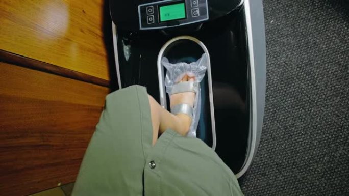自动热收缩鞋套覆膜机。特写。机器自动将鞋套涂在病人的鞋子上
