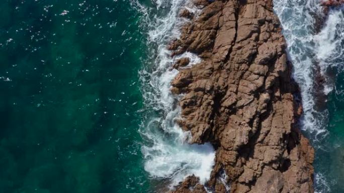 无人机航拍，海浪在多岩石的海岸上坠毁。悬崖俯视图