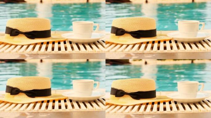 在夏天阳光明媚的日子里，一杯咖啡和一顶草帽在游泳池的背景上。早上好概念，并计划新的一天，一周，一个月