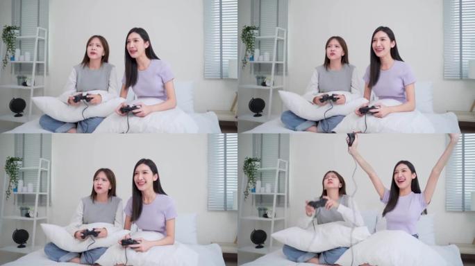 两个亚洲女人玩游戏和兴奋的朋友正在家里坐在床上玩电子游戏
