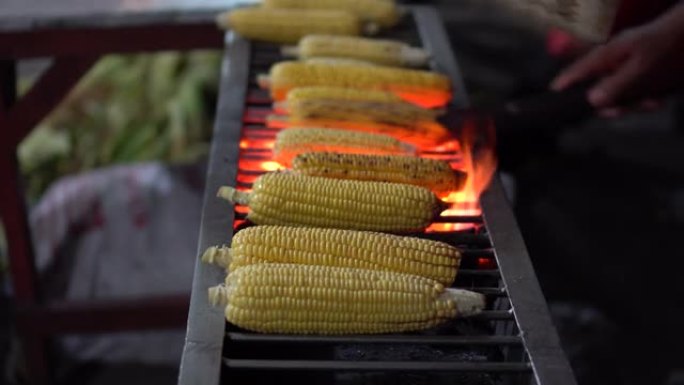 成熟的黄玉米用炭火烤。烧烤和烧烤过程。烤甜玉米是印尼夜间街头食品之一。