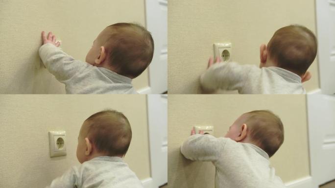 蹒跚学步的婴儿用手伸进家里墙上的电源插座。儿童手指免受电动休克的危险和保护