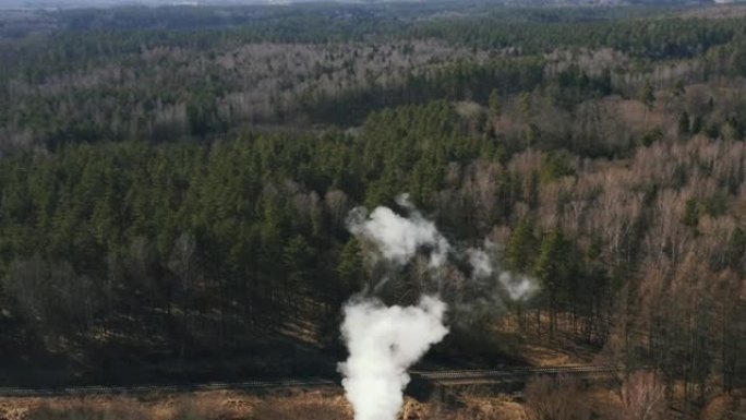 森林和河流附近工厂管道的鸟瞰图烟雾