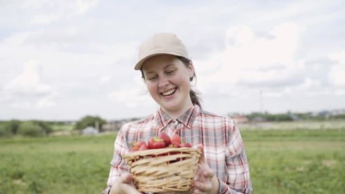 戴帽子的女人拿着草莓篮子。农民喜欢水果的香气。