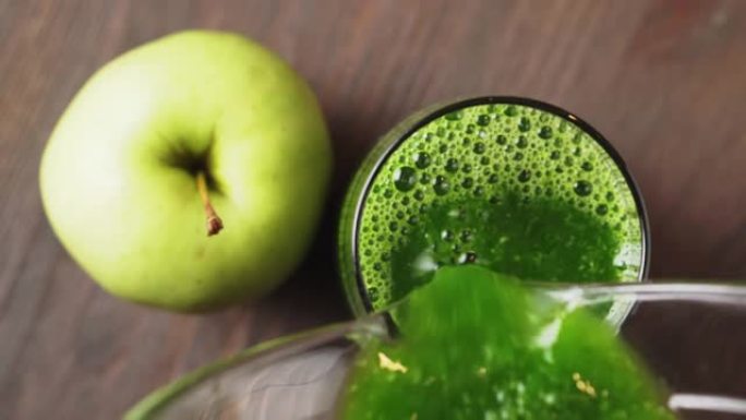 美味的绿色冰沙倒入玻璃，在木制背景上，俯视图。健康饮食的概念。