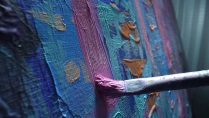 艺术家的画笔在画布上画油画。特写画笔将粉红色油漆的笔触涂到画布上。艺术家在创意工作坊中绘制当代艺术。