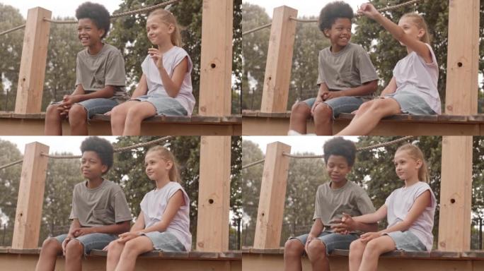 多种族男孩和女孩坐在户外手牵手