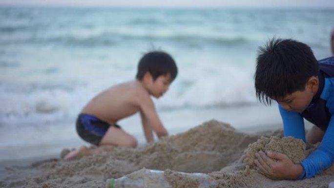 亚洲男孩兄弟在日落时在海滩上享受和玩海和沙子