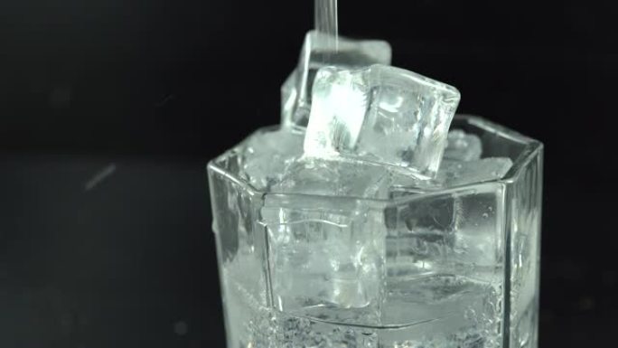将软饮料倒在玻璃杯中的冰上的宏观镜头。解渴。