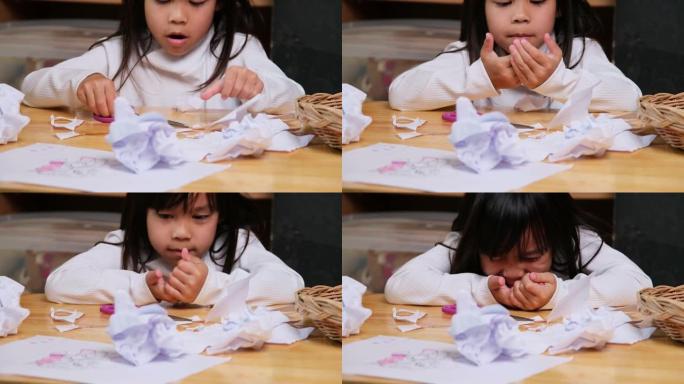 小女孩独自用剪刀剪纸，玩锋利的剪纸。家里处境危险的孩子。