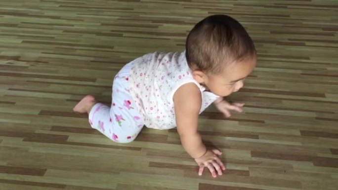 可爱的小女孩躺在地板上试图爬行