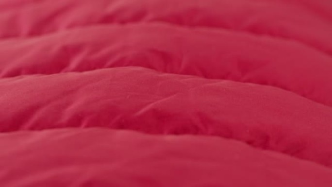 红色缝合织物特写。微距拍摄柔软温暖的防水材料，抽象背景。剪裁和缝纫概念