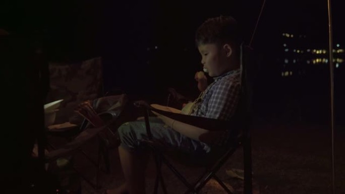 一个小男孩正在野营吃棉花糖