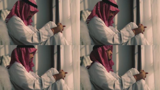 年轻的阿拉伯男子坐在卧室的地板上，表情沮丧地跪下。