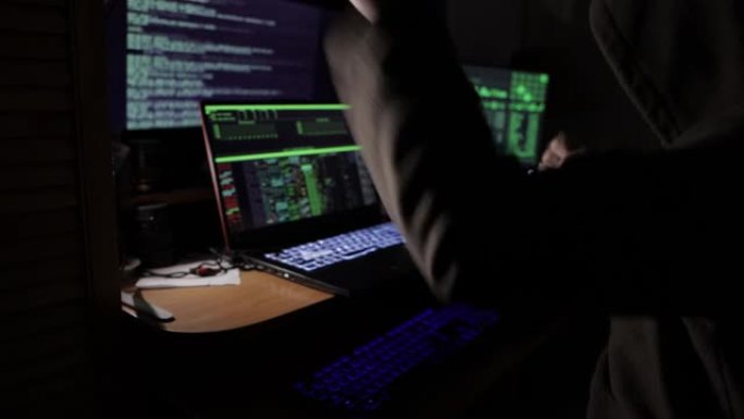 一名黑客坐在暗室里的显示器前，对着安全系统的入侵感到高兴