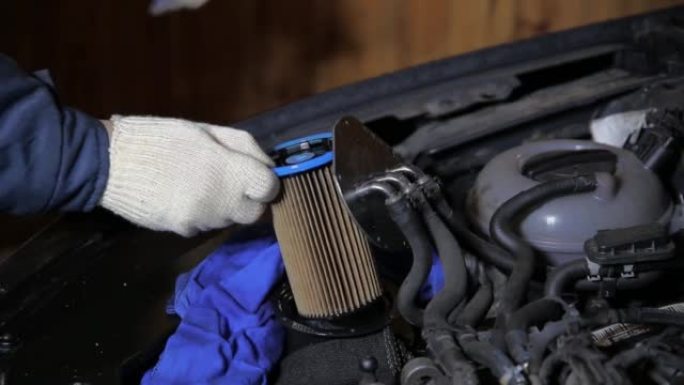 一名汽车修理工从汽车上拆下一个旧的脏燃油滤清器。车辆燃油系统维护，特写