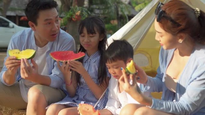 快乐的亚洲家庭在帐篷前度假吃西瓜