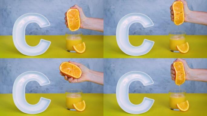 食品概念中的维生素c或抗坏血酸。人的手将橙子中的新鲜果汁挤压到灰色和黄色背景上的大陶瓷字母C附近的玻