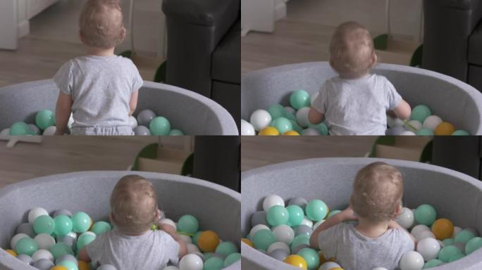 孩子在家打球。快乐的孩子在软球坑里，有五颜六色的球给幼儿，高加索男婴在家里玩得开心。