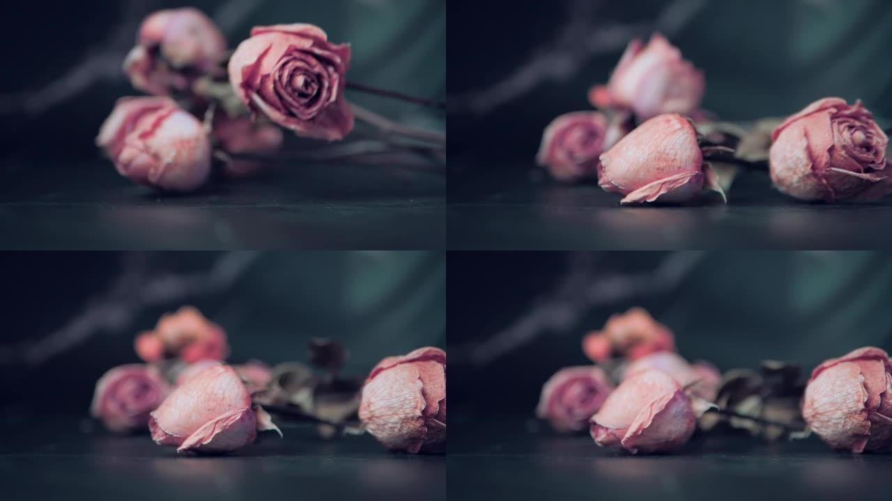 枯萎的玫瑰花朵落在黑色背景上，一束枯萎的玫瑰。枯萎的玫瑰的背景。枯萎的新娘花束。慢动作。