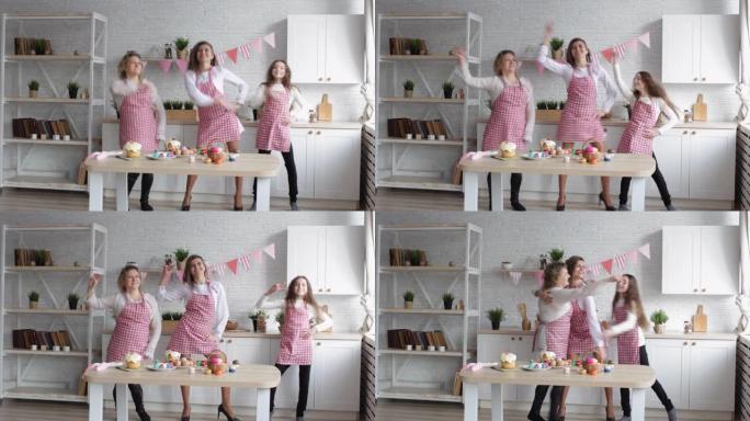 快乐的妈妈和她的女儿们在家庭厨房里跳舞和拥抱。
