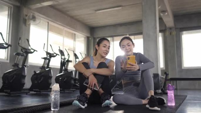4k亚洲女性朋友在健身馆锻炼时使用手机一起自拍。