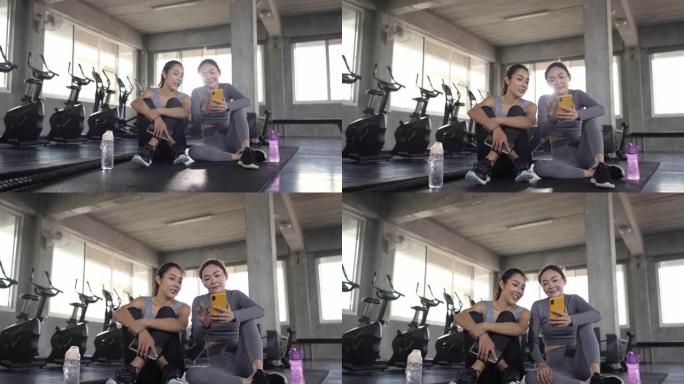 4k亚洲女性朋友在健身馆锻炼时使用手机一起自拍。
