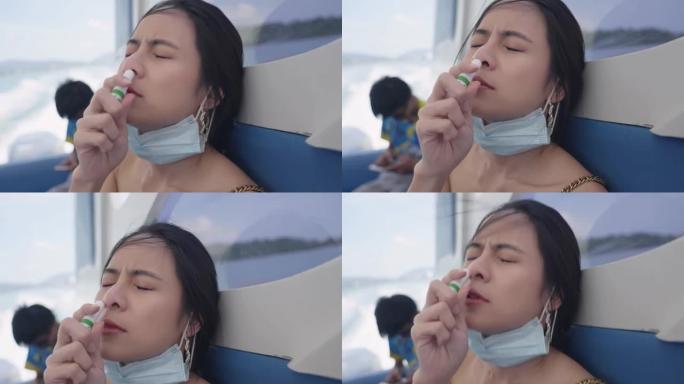 年轻迷人的亚洲女性游客在使用快艇运输时有晕船症状，一个恶心的女性呼吸吸气棒，替代草药治疗，暑假