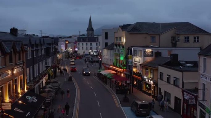 人们在夜城散步。街上餐馆前的室外露台。黄昏的城市。爱尔兰基拉尼