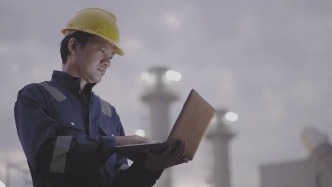 亚洲男子技术员手持笔记本电脑在工厂外工作