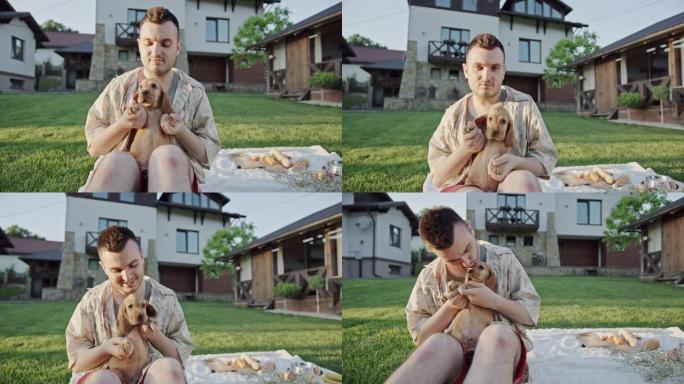 友谊狗男坐在房子附近的草坪上跳舞男亲吻小狗可卡犬动物爱