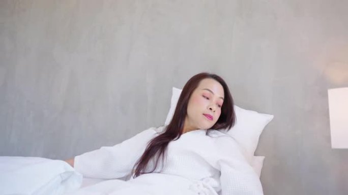 美丽的亚洲年轻女子放松睡在家里卧室的床上