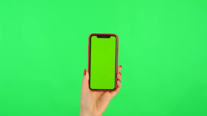 女人将带有工作区模拟屏幕的手机放在垂直位置的绿色背景上。女性手触摸、点击、滑动、拖动和滑动。特写