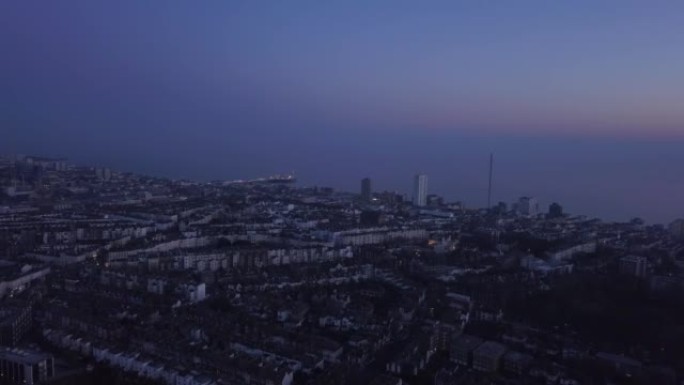 在日落前后拍摄的英格兰东南海岸布莱顿市的空中照片。向上倾斜显示火车站和城市延伸到远处。