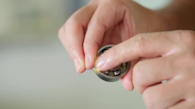 工人在实验室用手指将锂润滑脂放入小轴承中。手指上的黄色透明油脂。测试和服务概念。预防性维护和检查轴承