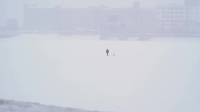 一个孤独的人穿过白雪皑皑的荒原，拖着物资。