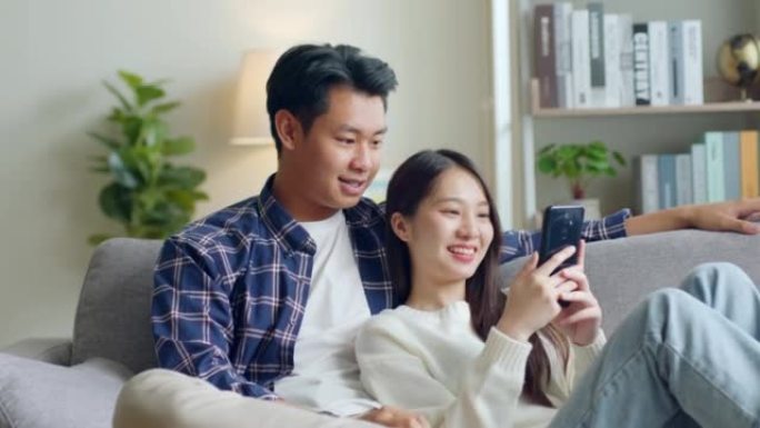 亚洲情侣男女使用手机，在家里共度时光，亚洲情侣家庭生活理念
