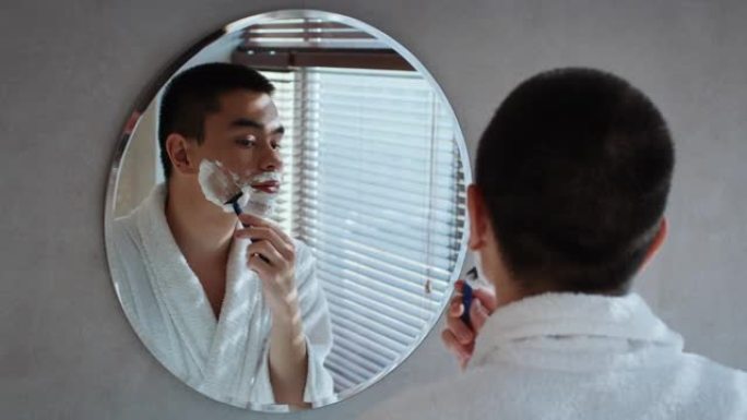 日本男子剃光面站在浴室镜子附近
