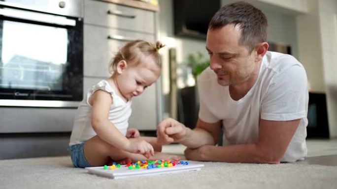 可爱的小女孩玩蘑菇指甲马赛克。父亲和婴儿一起玩的概念。爱好和休闲时间