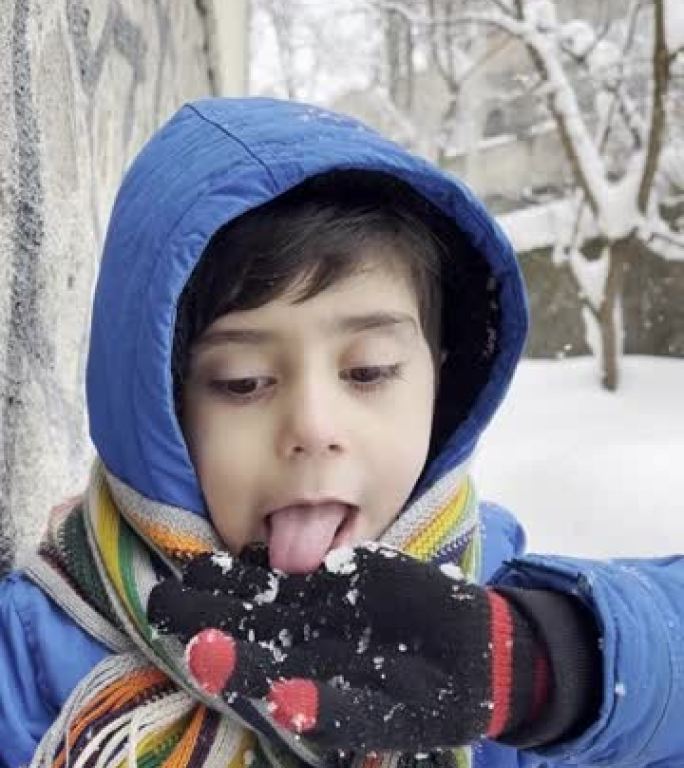 穿着蓝色冬装的有趣小男孩在降雪时行走。孩子们的户外冬季活动。