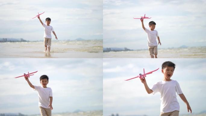 亚洲孩子在海滩玩纸板飞机