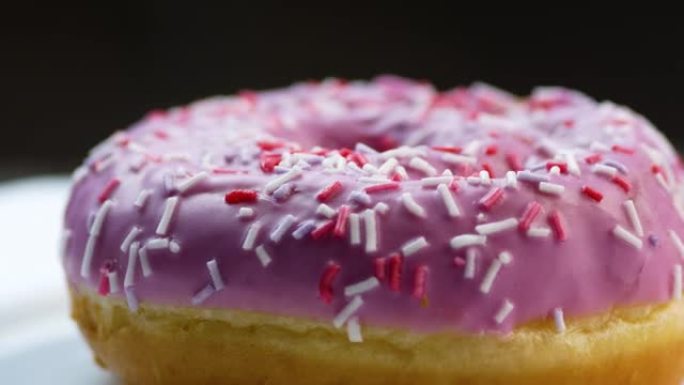 覆盖着粉红色糖霜的甜甜甜圈的特写镜头旋转。早餐甜点。日常食物。轻质快速碳水化合物。新鲜烘焙食品。选择
