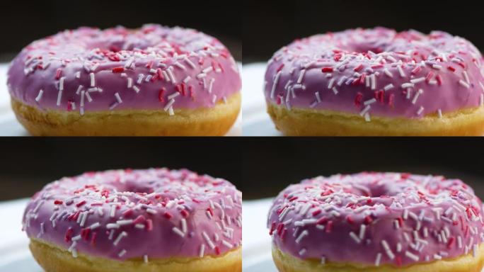 覆盖着粉红色糖霜的甜甜甜圈的特写镜头旋转。早餐甜点。日常食物。轻质快速碳水化合物。新鲜烘焙食品。选择