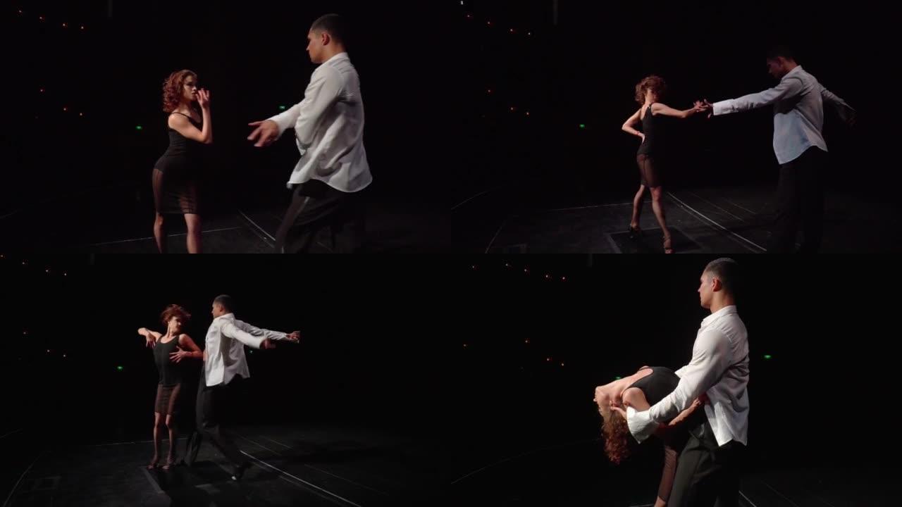 交际舞舞者在黑暗的舞台上以拉丁美洲风格激情舞蹈，摆动手臂，转身。男人抓住女人的肩膀，欲望使她弯腰，然